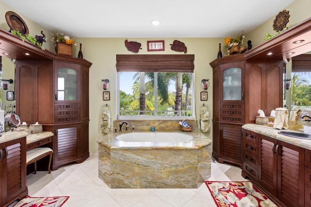 bathroom with tile patterned flooring, plenty of natural light, vanity, and tiled bath