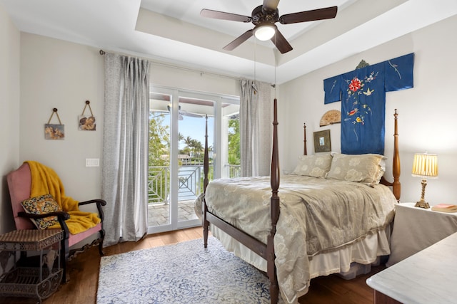 bedroom featuring a raised ceiling, ceiling fan, dark hardwood / wood-style flooring, and access to exterior