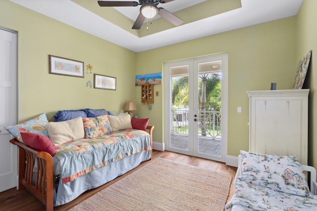 interior space with a tray ceiling, ceiling fan, french doors, and light hardwood / wood-style flooring