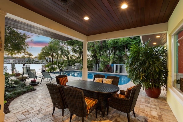 patio terrace at dusk featuring a fenced in pool