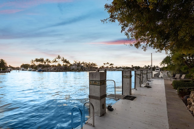 patio terrace at dusk featuring a water view and a boat dock