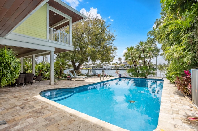 view of pool featuring a patio area, ceiling fan, and a water view