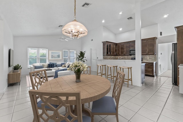 dining room featuring high vaulted ceiling, light tile patterned flooring, an inviting chandelier, and a textured ceiling