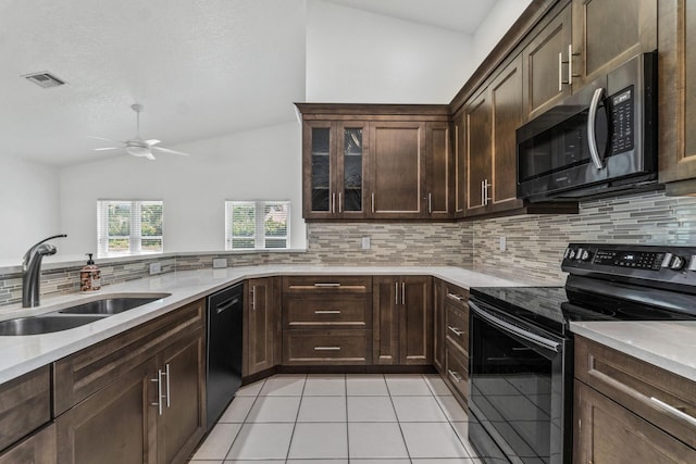 kitchen featuring backsplash, vaulted ceiling, black appliances, dark brown cabinetry, and sink