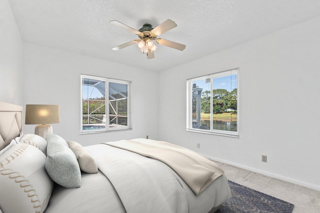 bedroom with ceiling fan, carpet, multiple windows, and a textured ceiling