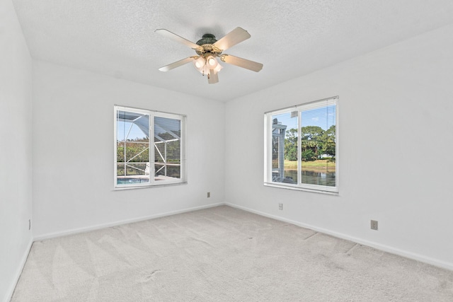 spare room with ceiling fan, light colored carpet, and a wealth of natural light