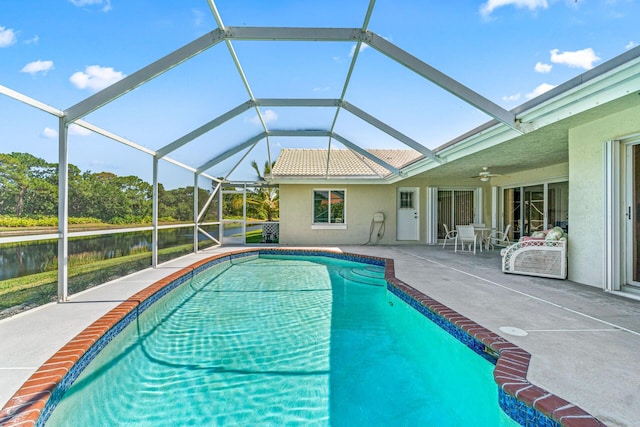 view of swimming pool with ceiling fan, glass enclosure, and a patio area