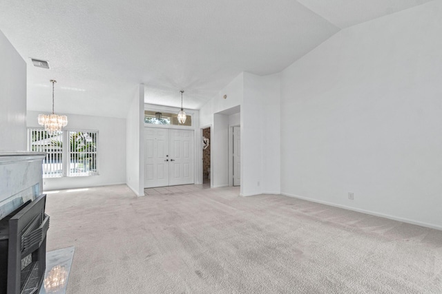 unfurnished living room with a textured ceiling, a notable chandelier, vaulted ceiling, light colored carpet, and a tile fireplace