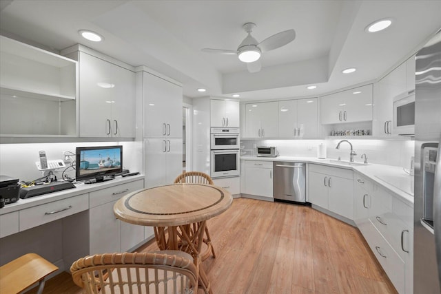 kitchen with ceiling fan, multiple ovens, white cabinets, dishwasher, and light wood-type flooring