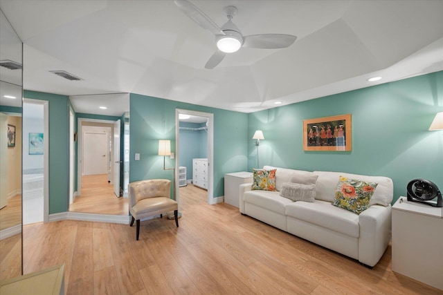 living room featuring hardwood / wood-style floors, ceiling fan, and a raised ceiling