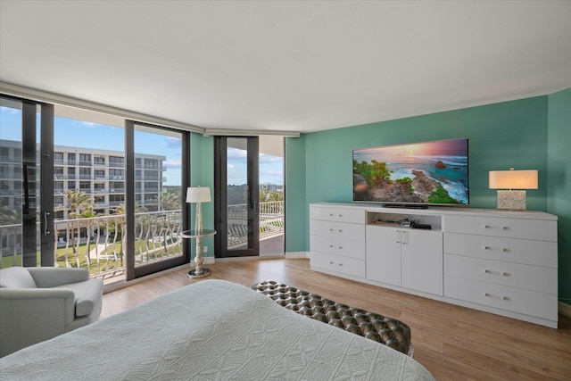 bedroom featuring expansive windows, light hardwood / wood-style floors, and access to outside