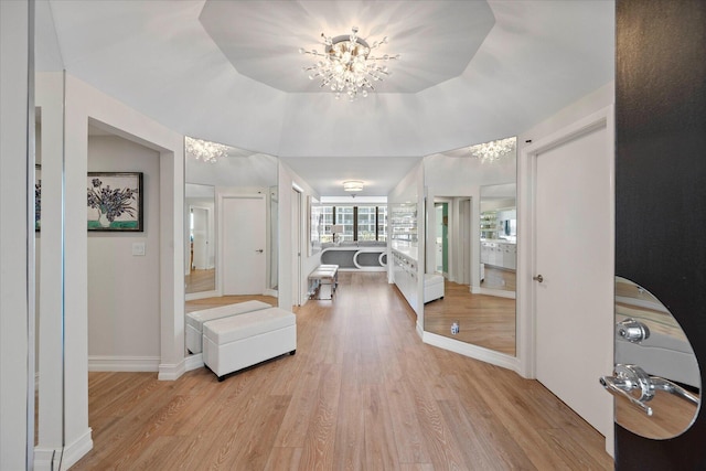 foyer with light hardwood / wood-style flooring, a raised ceiling, and an inviting chandelier