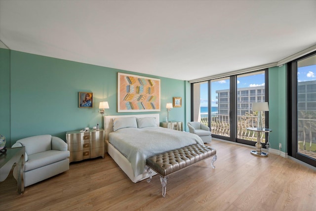 bedroom featuring floor to ceiling windows, hardwood / wood-style flooring, and access to exterior