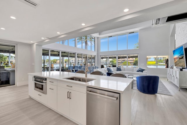 kitchen featuring plenty of natural light, white cabinetry, stainless steel appliances, and an island with sink