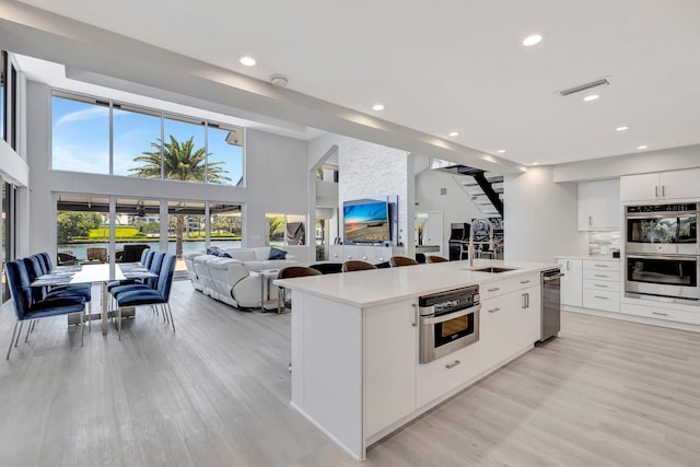 kitchen featuring double oven, white cabinetry, a kitchen island, and a high ceiling