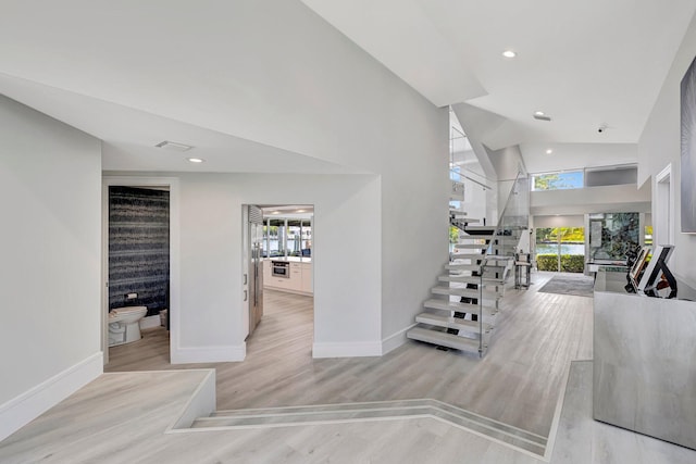 stairway featuring hardwood / wood-style floors, plenty of natural light, and high vaulted ceiling