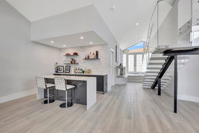 bar with light hardwood / wood-style floors, white cabinetry, and vaulted ceiling