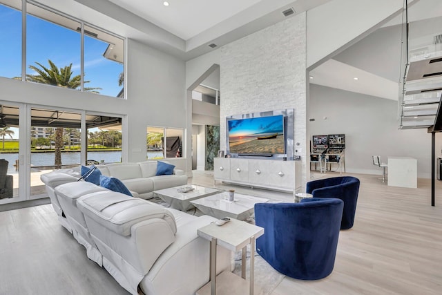 living room featuring a high ceiling, a water view, and light hardwood / wood-style flooring