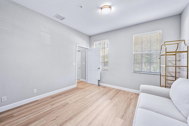 living area with light hardwood / wood-style flooring, a healthy amount of sunlight, and a textured ceiling