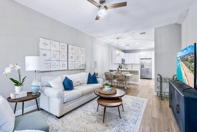 living room with a textured ceiling, sink, ceiling fan, and light hardwood / wood-style floors