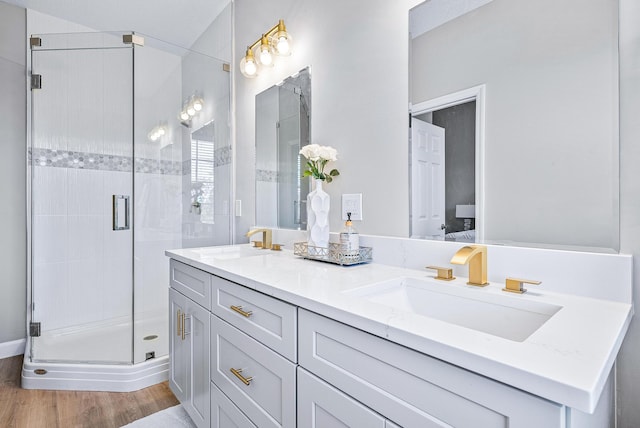 bathroom featuring dual sinks, wood-type flooring, an enclosed shower, and large vanity