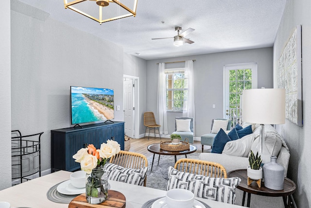 living room featuring light hardwood / wood-style flooring, ceiling fan, and a textured ceiling