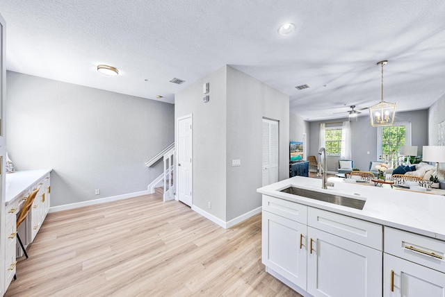 kitchen featuring light hardwood / wood-style floors, hanging light fixtures, white cabinetry, and sink