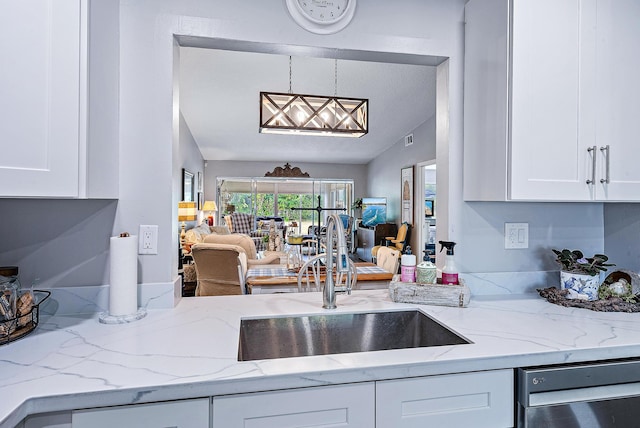 kitchen featuring decorative light fixtures, vaulted ceiling, dishwasher, and white cabinets