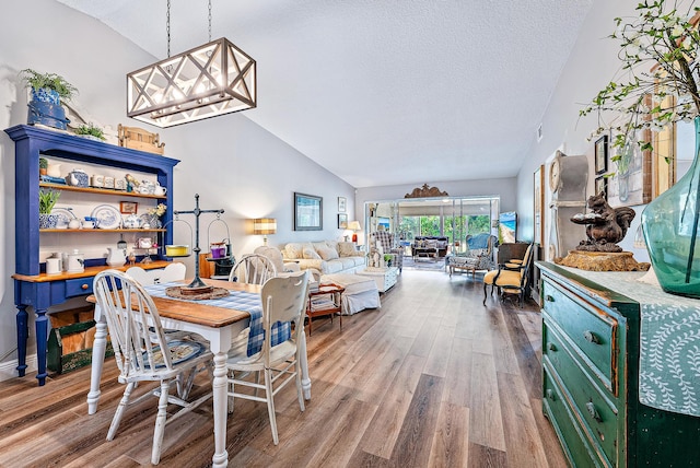 dining room featuring wood-type flooring, a textured ceiling, and high vaulted ceiling