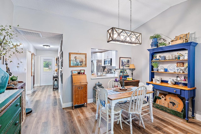 dining space featuring a textured ceiling, hardwood / wood-style floors, and lofted ceiling