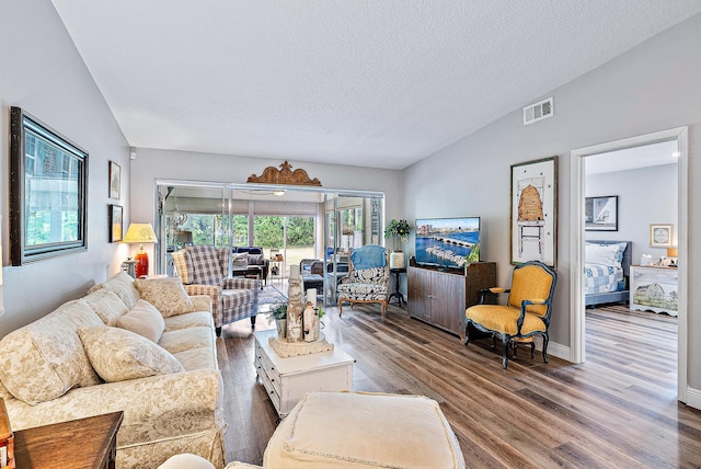 living room with wood-type flooring, lofted ceiling, and a textured ceiling