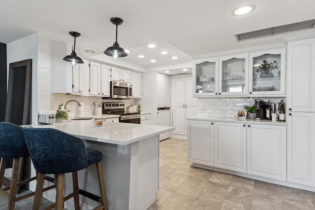 kitchen with hanging light fixtures, light tile flooring, white cabinetry, appliances with stainless steel finishes, and tasteful backsplash