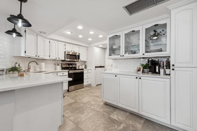 kitchen featuring hanging light fixtures, backsplash, sink, and stainless steel appliances