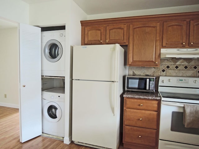 kitchen with backsplash, light hardwood / wood-style floors, stacked washing maching and dryer, and white appliances