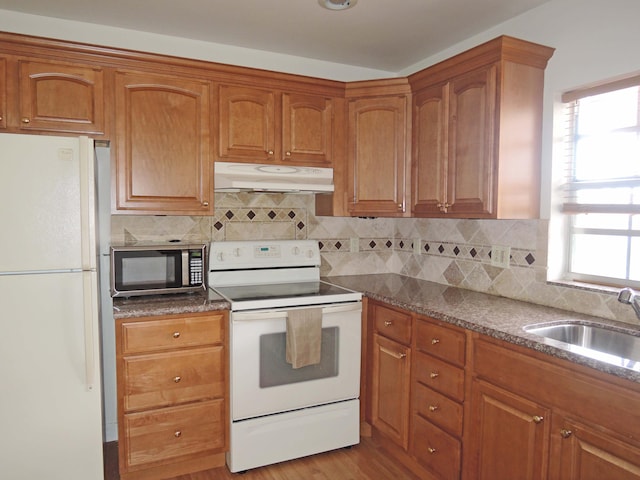 kitchen with light hardwood / wood-style floors, white appliances, tasteful backsplash, and sink