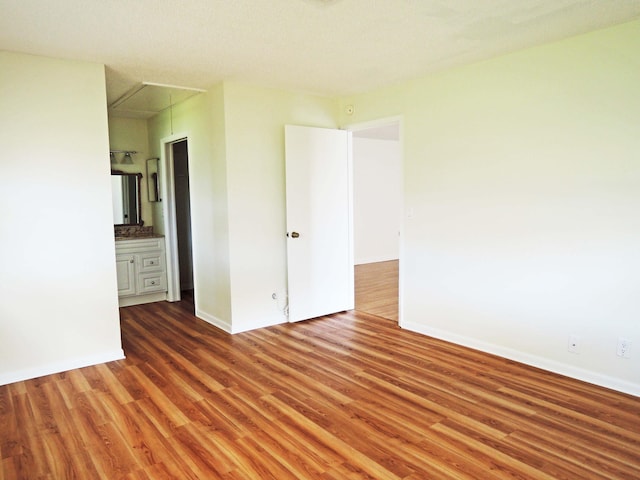 unfurnished bedroom featuring hardwood / wood-style flooring and ensuite bathroom