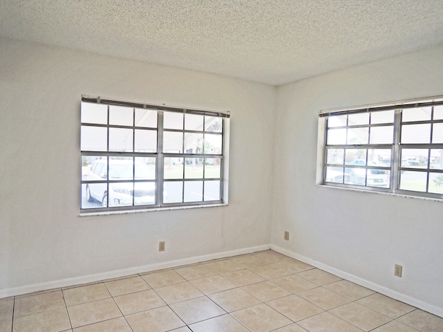 tiled empty room with plenty of natural light and a textured ceiling