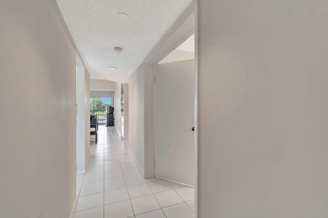 corridor featuring light tile patterned flooring and a textured ceiling