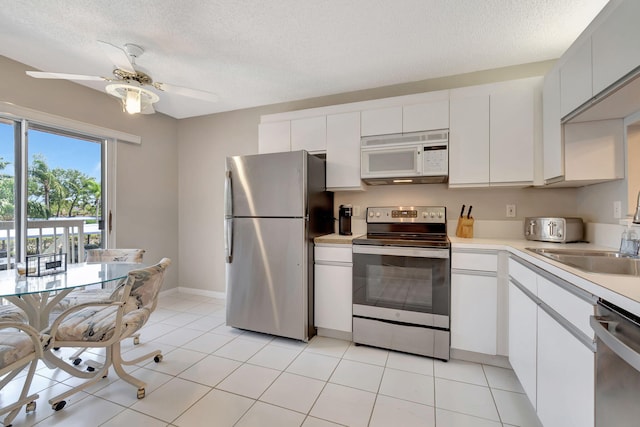 kitchen with white cabinetry, sink, ceiling fan, light tile patterned floors, and appliances with stainless steel finishes