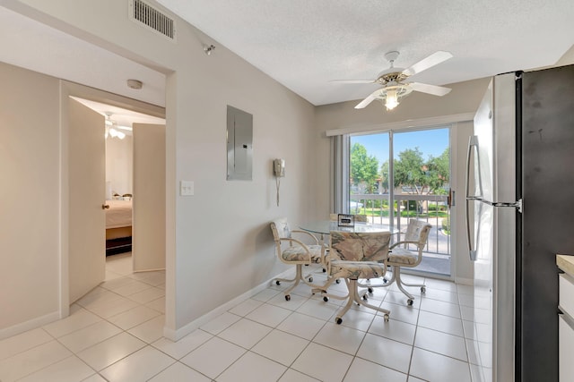 dining room featuring ceiling fan, light tile patterned floors, a textured ceiling, and electric panel