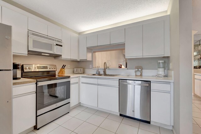 kitchen featuring white cabinetry, sink, stainless steel appliances, a textured ceiling, and light tile patterned flooring