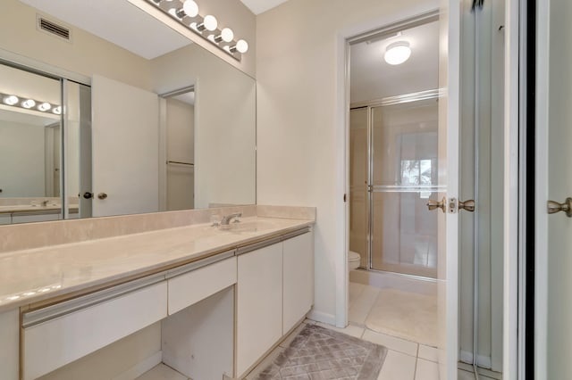 bathroom featuring tile patterned floors, vanity, a shower with shower door, and toilet