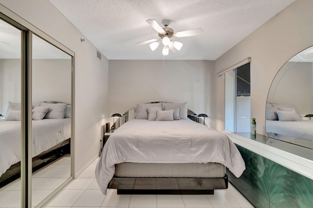 bedroom with ceiling fan, light tile patterned floors, and a textured ceiling