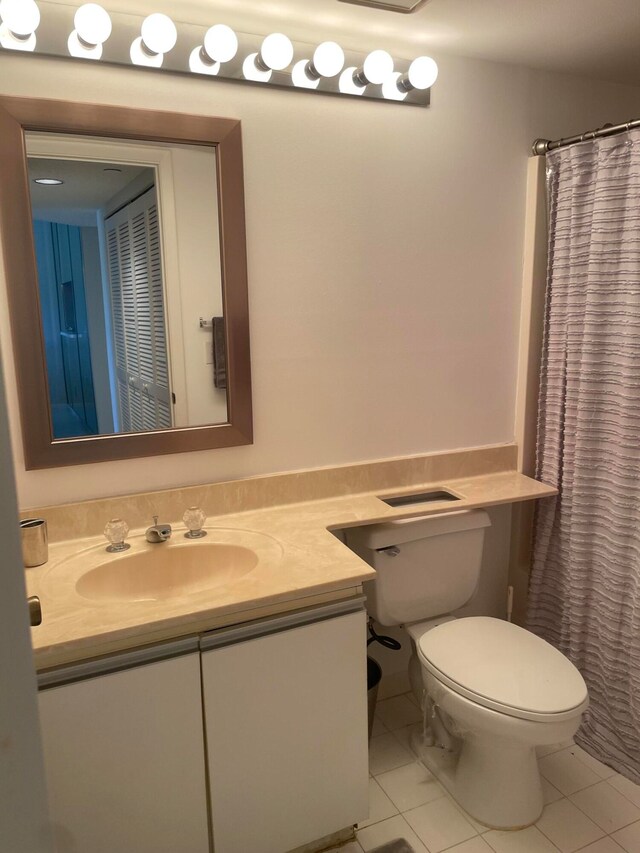 bathroom featuring tile patterned floors, vanity, curtained shower, and toilet