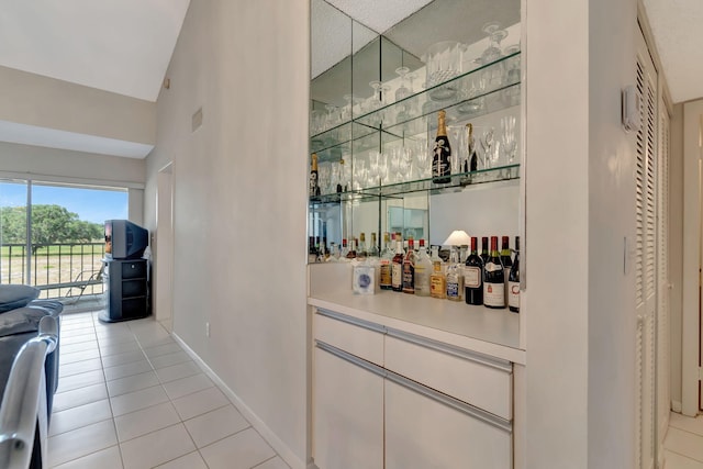 bar with light tile patterned floors and vaulted ceiling