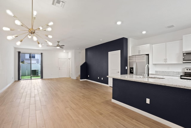 kitchen with white cabinets, ceiling fan with notable chandelier, sink, light stone countertops, and appliances with stainless steel finishes