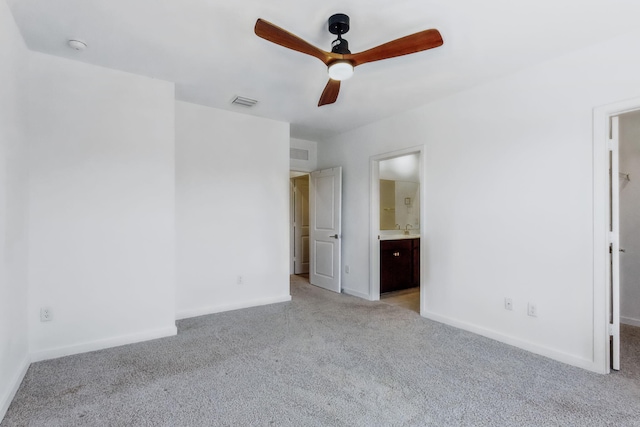 unfurnished bedroom with ceiling fan, light colored carpet, and ensuite bath