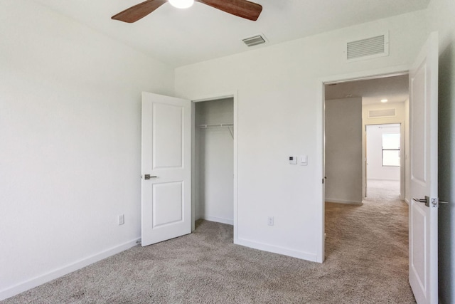 unfurnished bedroom featuring ceiling fan, light colored carpet, and a closet