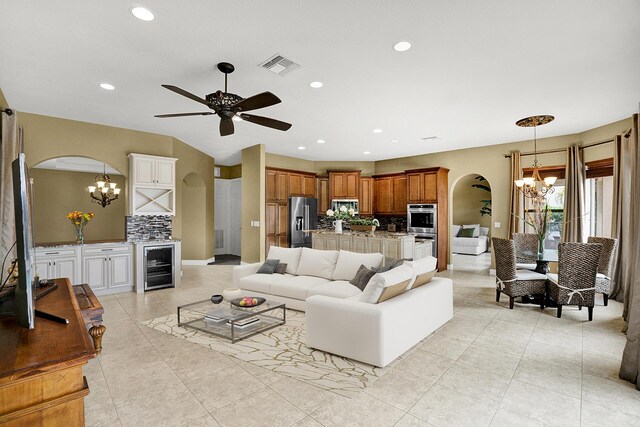 living room featuring sink, light tile patterned floors, beverage cooler, and ceiling fan with notable chandelier