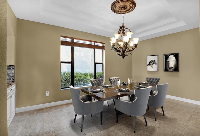 dining area with light tile patterned floors, an inviting chandelier, and a raised ceiling